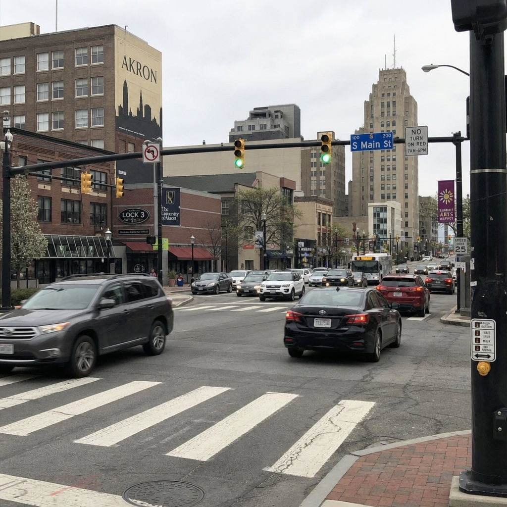 Downtown Akron, Ohio, intersection on South Main Street with traffic, crosswalks, traffic signals, and surrounding buildings.